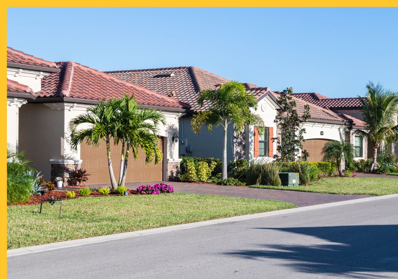 Tropical-style suburban homes with terracotta roofs, palm trees, and manicured landscaping on a sunny day