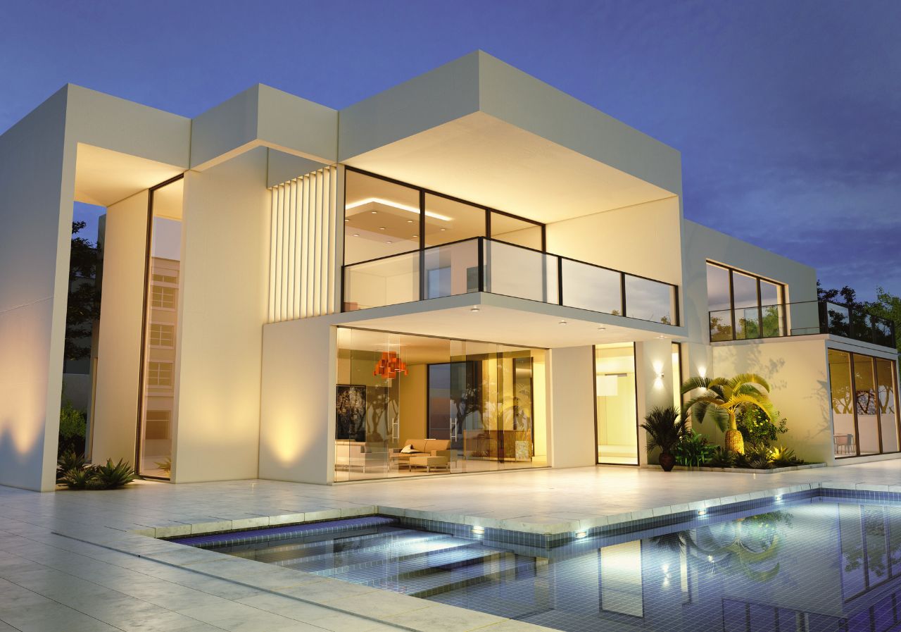 Modern luxury home with large glass windows, illuminated exterior, and a swimming pool reflecting the lights at dusk