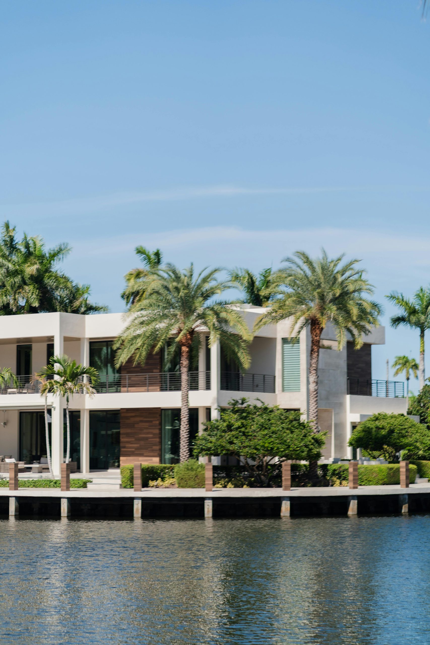Modern waterfront luxury home with palm trees overlooking a waterfront in Florida